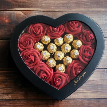 Ferrero Rocher op een hart omringt door rode rozen in een zwart hartvormige doos