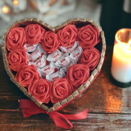 Raffaellos op een hart omringt met roden rozen. Het hart is aan de buitenkant omringt met Merci chocolaatjes