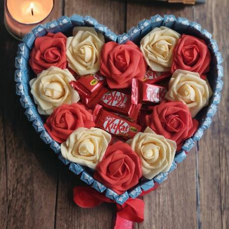 Ki Kat minis op een hart omringt met rode en witte rozen. Het hart is omringt met chocolaatjes huismerk