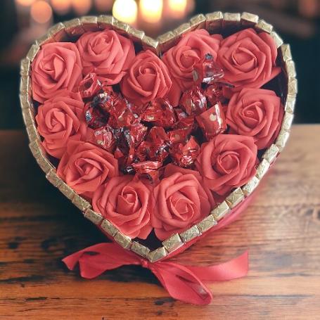 Malteser bonbons op een hart omringt met rode rozen. Het hart zelf is omringt met Merci chocolaatjes
