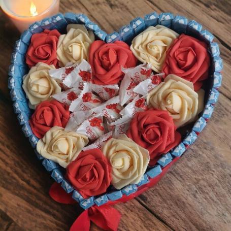 Raffaellos omringt met rode rozen op een hart. Het hart zelf is omringt met chocolaatjes huismerk