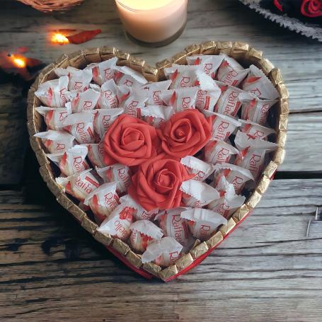Een hart vol Raffaello's met 3 rode foam rozen in het midden.