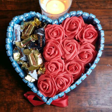 Een hart met aan een kant toblerone mix mini's en aan de andere kant 10 rode rozen. Omringt door chocolaatjes huismerk in bla