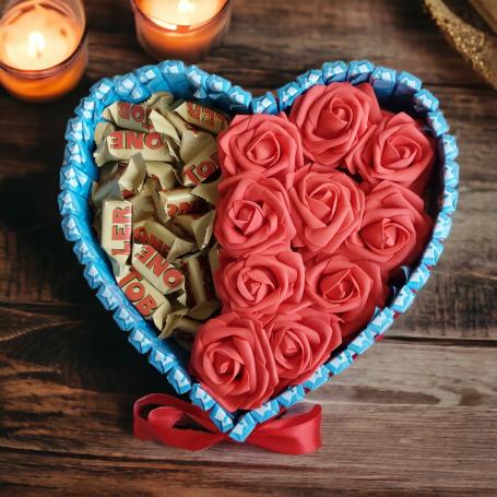 hart met aan de ene helft toblerone en aan de andere helft rode foam rozen. Omringt door chocolaatjes in blauwe verpakking