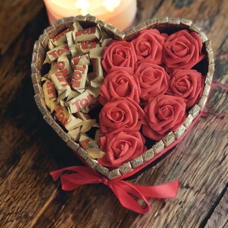 Een hart met aan de linker kant Toblerone minis en aan de rechter kant 9 rode foam rozen