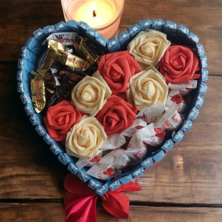 Raffaellos en Toblerone mix minis op een hart gescheiden door een strook van witte en rode rozen. Het hart is omringt met cho